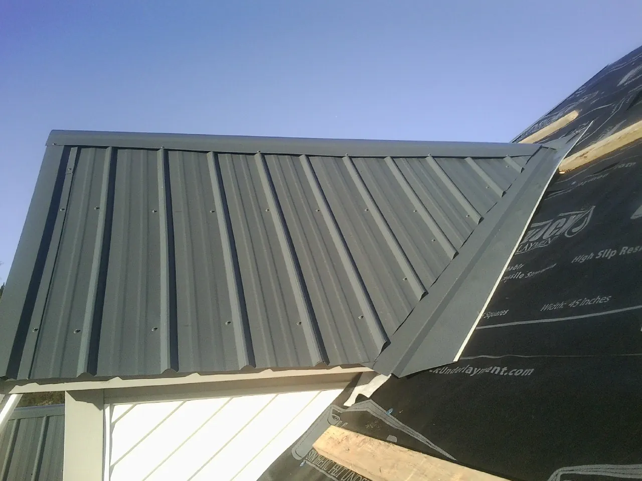 Gray metal roof panels going on over a garage gable in Scammon