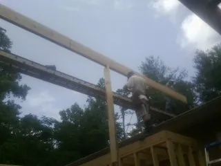 Carpenter setting a ridge beam over a new addition frame — Ice Dam Removal by Roofing Brothers in Scammon