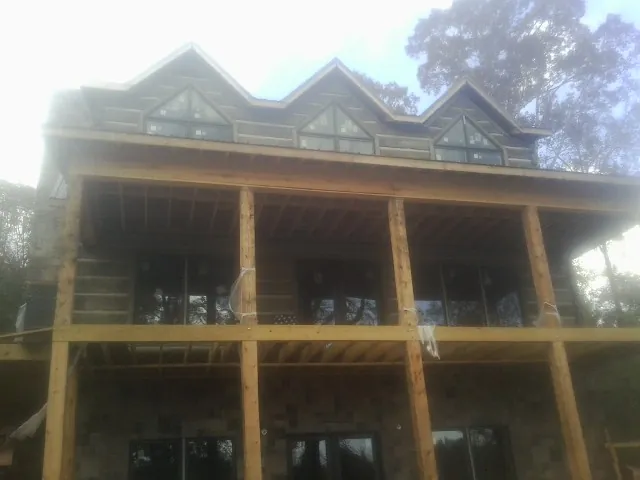 Dormers and porch framing on a large log home under construction — Roof Coating work by our crew in Scammon