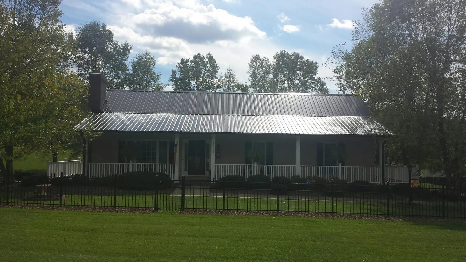 Gray metal roof on a brick ranch with a full width front porch — Gutter Guard Installation work by our crew in Scammon