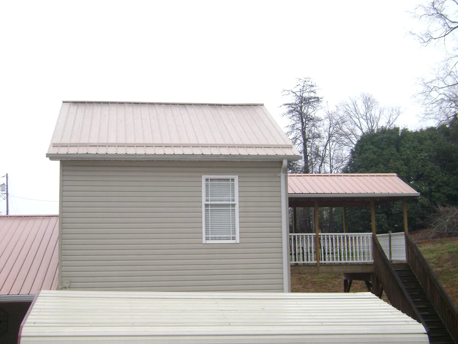 Tan metal roofs on a two story addition and attached porch, from a Roof Replacement job in Scammon